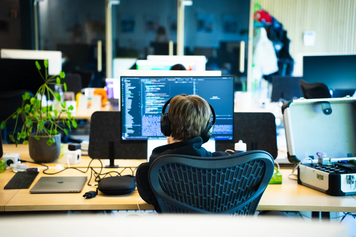 A developer at their desk, code open on the screen