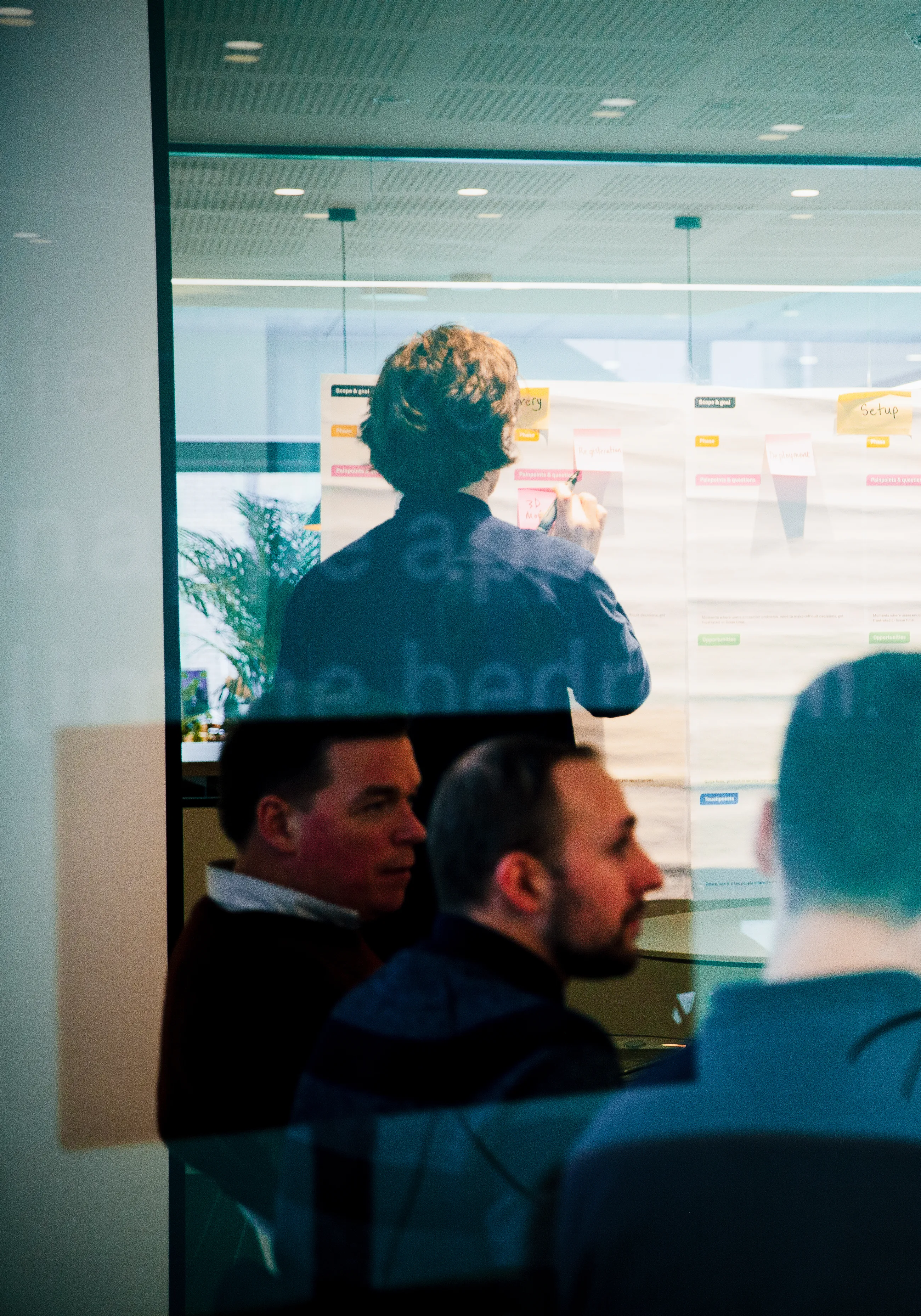 A team mapping a product journey across a wall of sticky notes